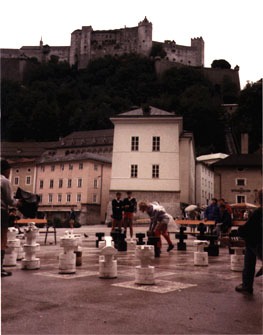 Qualo playing outdoor chess under castle in the rain (Salzburg, Austria).