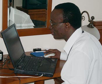 Daniel_Nsibambi working feverishly to file his report. Copyright  Jerry Bibuld, 2002.