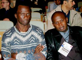 Felix Malata (ZIM), Captain of the Women's Team (wearing a sweater) and David Zulu (ZAM) Captain of the Men's Team (wearing a leather jacket). Copyright © Jerry Bibuld, 2002.