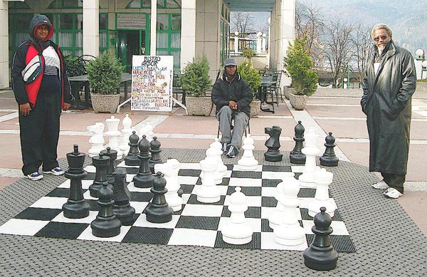 'Trini' Lawn Chess... Cecil Lee (TRI Captain), right, has just defeated Ravishen Singh (TRI Bd. 5), left, on the outdoor set in the Kompas Shopping Center. The witness is FM Ryan Harper (TRI Bd. 1), center. Copyright © Jerry Bibuld, 2002.