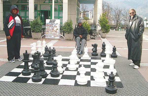 'Trini' Lawn Chess... Cecil Lee (TRI Captain), right, has just defeated Ravishen Singh (TRI Bd. 5), left, on the outdoor set in the Kompas Shopping Center. The witness is FM Ryan Harper (TRI Bd. 1), center. Copyright  Jerry Bibuld, 2002.