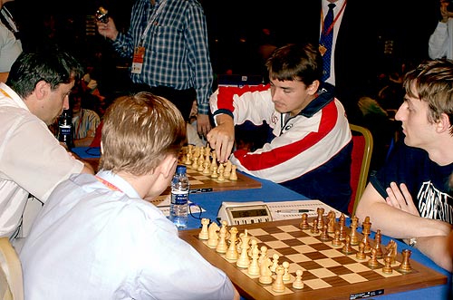Morozevich (RUS) adjusting the pieces against Ivanchuk (UKR) while Ponomariov (near left) and  Grischuk look on. Photo by Paul Truong.