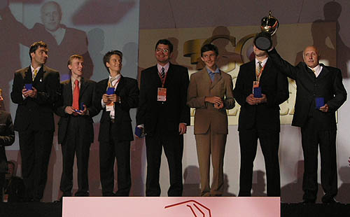 Ukrainian team captain Vladimir Tukmakov raises trophy in victorious celebration as the players look on.