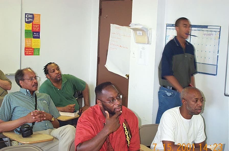 Onlookers in the analysis room including Willie 'Pop' Johnson (back), NMs Frank Street (blue checkered shirt) and Glenn Bady (red-orange shirt).  Copyright ©, Daaim Shabazz.