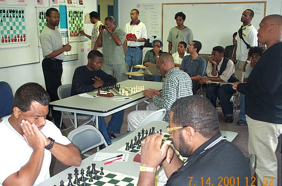 Top: Simutowe (L) vs. Schleifer; Bottom: Simpson (L) vs. Rogers.  IM Watu Kobese (far right) stands while waiting on FM William Morrison.  Copyright , Daaim Shabazz.