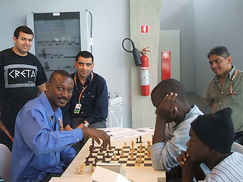 IM Odion Aikhoje blitzing with Zambia's Chitumbo Mwali at 2006 Olympiad. Jamaica's Shane Matthews is standing on the right.