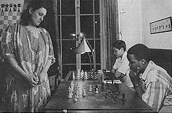 Above is K.K. Karanja (seated) playing GM Maya Chiburdanidze in a simultaneous exhibition at the Marshall Chess Club in 1987. At the time, Maya was the Women's World Champion.  Photograph by Nigel Eddis.