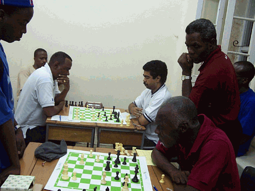 Background: FM Philip Corbin in a 4th round battle versus Dirk Austin while Terry Farley looks on. Foreground: Othneil Harewood ponders what would become a winning strategy against Mark-John Alleyne. Photo by Barbados Chess Federation.