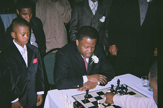 GM Maurice Ashley playing blitz with Kasaun Henry while onlookers take note. Photo by Kevin Fite.