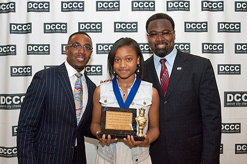 Michaela White of Detroit International Academy honored by WDIV's Chauncey Glover and Councilman James Tate. Photo by Detroit City Chess Club.