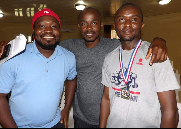 Left to Right: Former Champions James Stephen Tondo III and FM Barcon Harmon with Thomas Saah wearing his championship medal. Photo by Mario Kpan