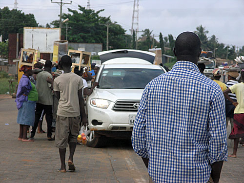 A car being mobbed by street vendors.