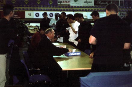 Team Captains submitting lineup cards. Chief Arbiter Geurt Gijssen is seated (near left). Copyright  Ian Wilkinson, 2002.