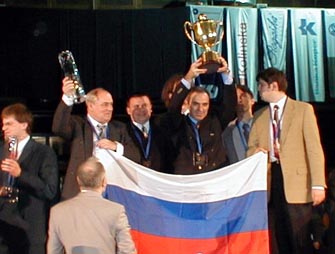 Garry Kasparov triumphantly hoisting the Winner's Cup as the Russian squad looks on.
