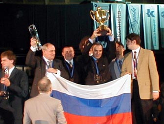 GM Garry Kasparov triumphantly hoisting the Winner's Cup as the Russian squad looks on.