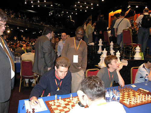 Ugandas Grace Nsubuga peers at Michael Adams game. Luke McShane waits for his opponent to show up. The crowd on the stage is packed around Ukraines board.