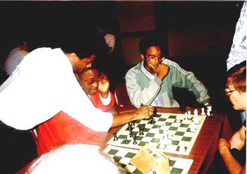 Maurice Ashley analyzing R.O. Mitchell's game (with his seated opponent) at the 1989 U.S. Open in Chicago. Kimani Stancil looks on. R.O. Mitchell came from nowhere to win the U.S. Junior Open in 1990. After winning his Master's title, he disappeared from active play. Stancil, also a young star in this picture, earned his Ph.D. in Physics from MIT in 2002. Copyright © 1989, Daaim Shabazz.