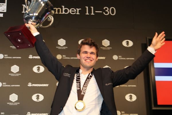 Carlsen hoists champion's trophy.
