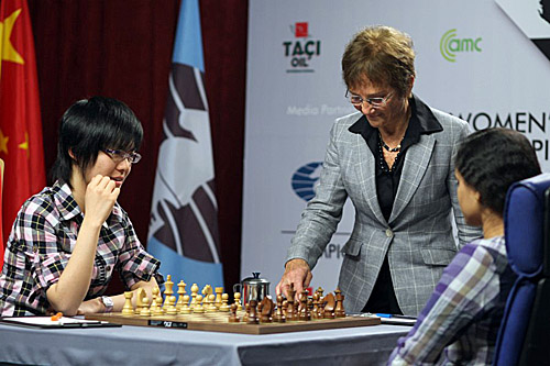 International Arbiter Carol Jarecki starts the clock for Hou Yifan in Game #7. Photo by Anastasiya Karlovich for FIDE.