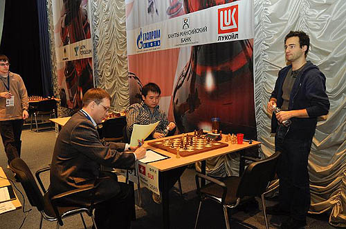 China's Li Chao reflects on the game just completed with Yannick Pelletier of Switzerland (standing). Maxime Vachier-Lagrave observes.