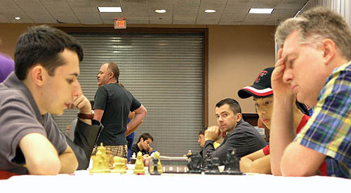 GM Aleksander Lenderman playing GM Sergey Kudrin. GM Alexander Onischuk peering at camera. Photo by Daaim Shabazz.