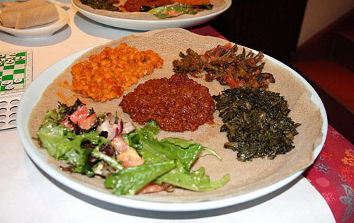 Delicious Ethiopian cuisine from Enjera Restaurant, 549 S. 23rd Street, Arlington, VA. This is the vegetable platter with green salad, split peas, spicy lentils, alicha and greens. It sits on a bed of injera bread which is made of teff flour. Highly nutritious! Photo by Daaim Shabazz.